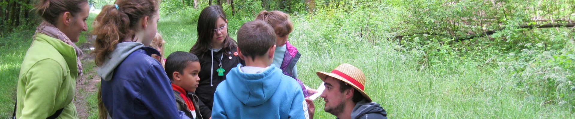 animatrice avec groupe d'enfants à la découverte de la nature