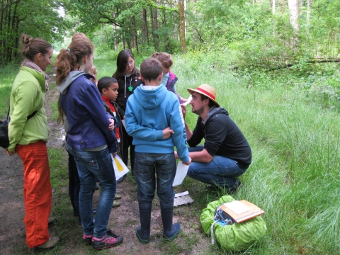 animatrice avec groupe d'enfants à la découverte de la nature